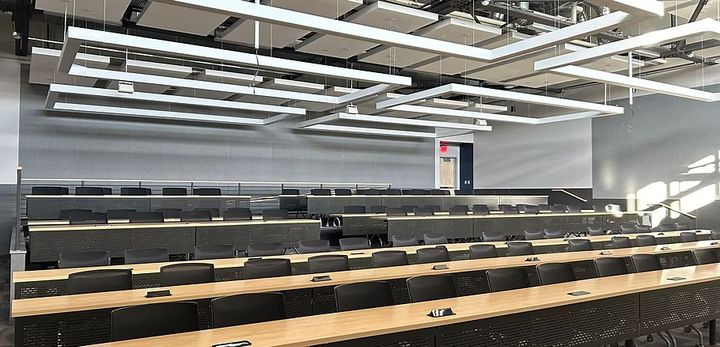 A large lecture hall with rows of tables and chairs.