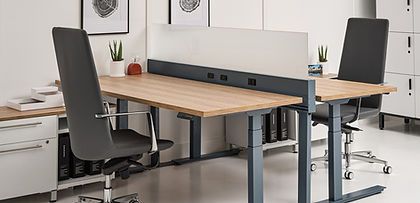 A couple of standing desks with chairs in an office.