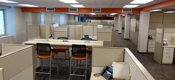 A cubicle in an office with a table and chairs