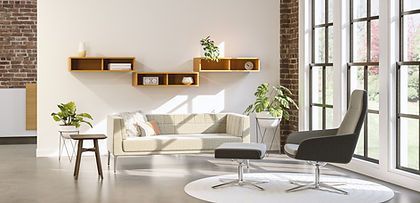 A living room with a couch , chair , ottoman and shelves.