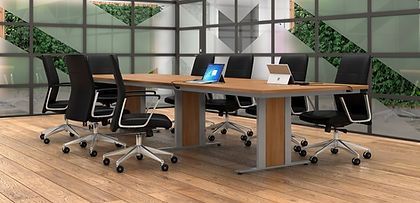 A conference room with a long table and chairs and a laptop on the table.
