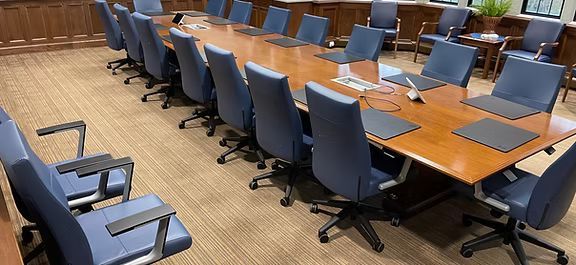 A conference room with a long wooden table and blue chairs.