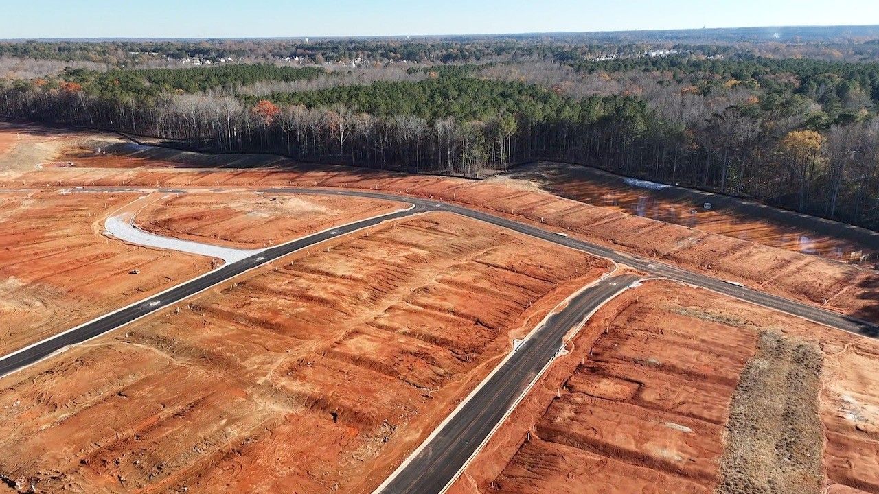 An aerial view of a construction site surrounded by trees and dirt. tamarack land development