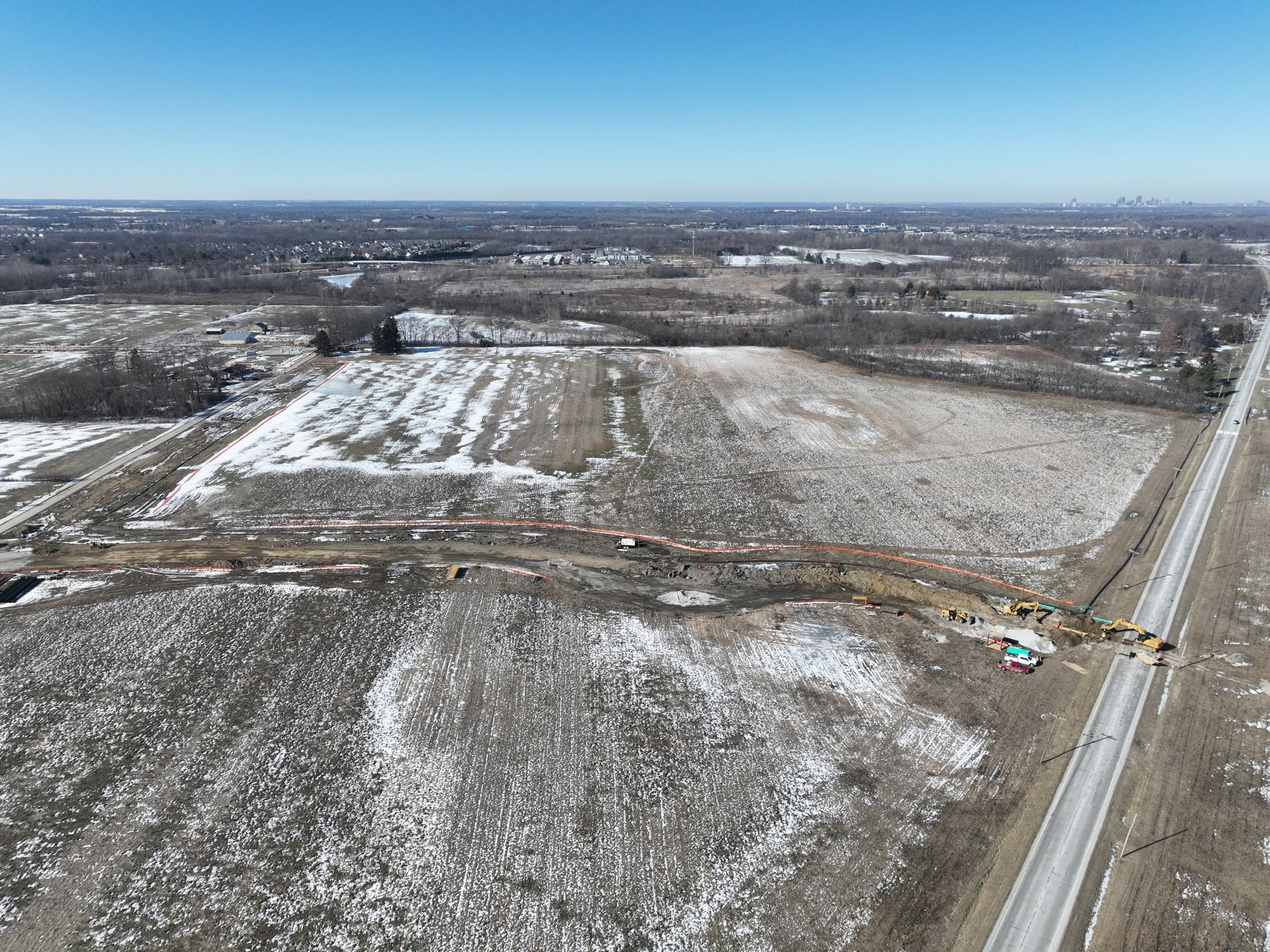 An aerial view of a snowy field next to a highway.