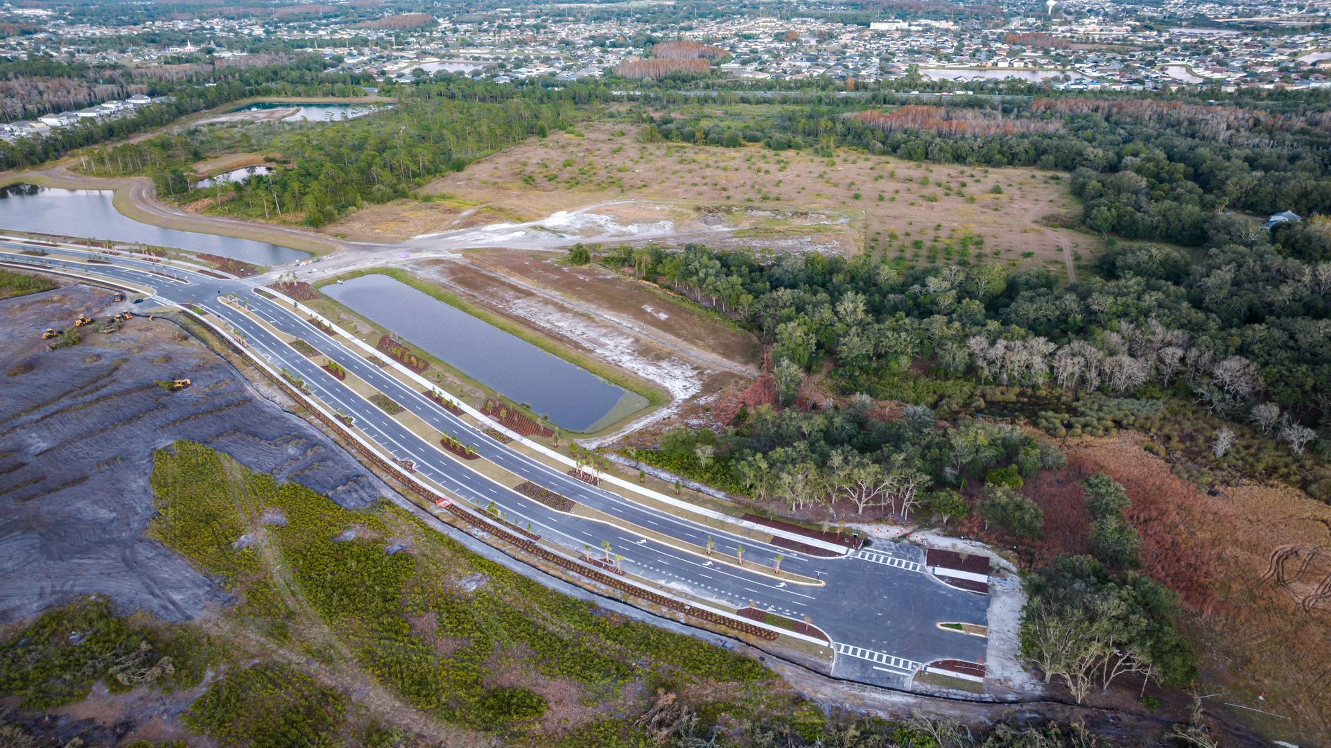 An aerial view of a bridge over a river surrounded by trees.