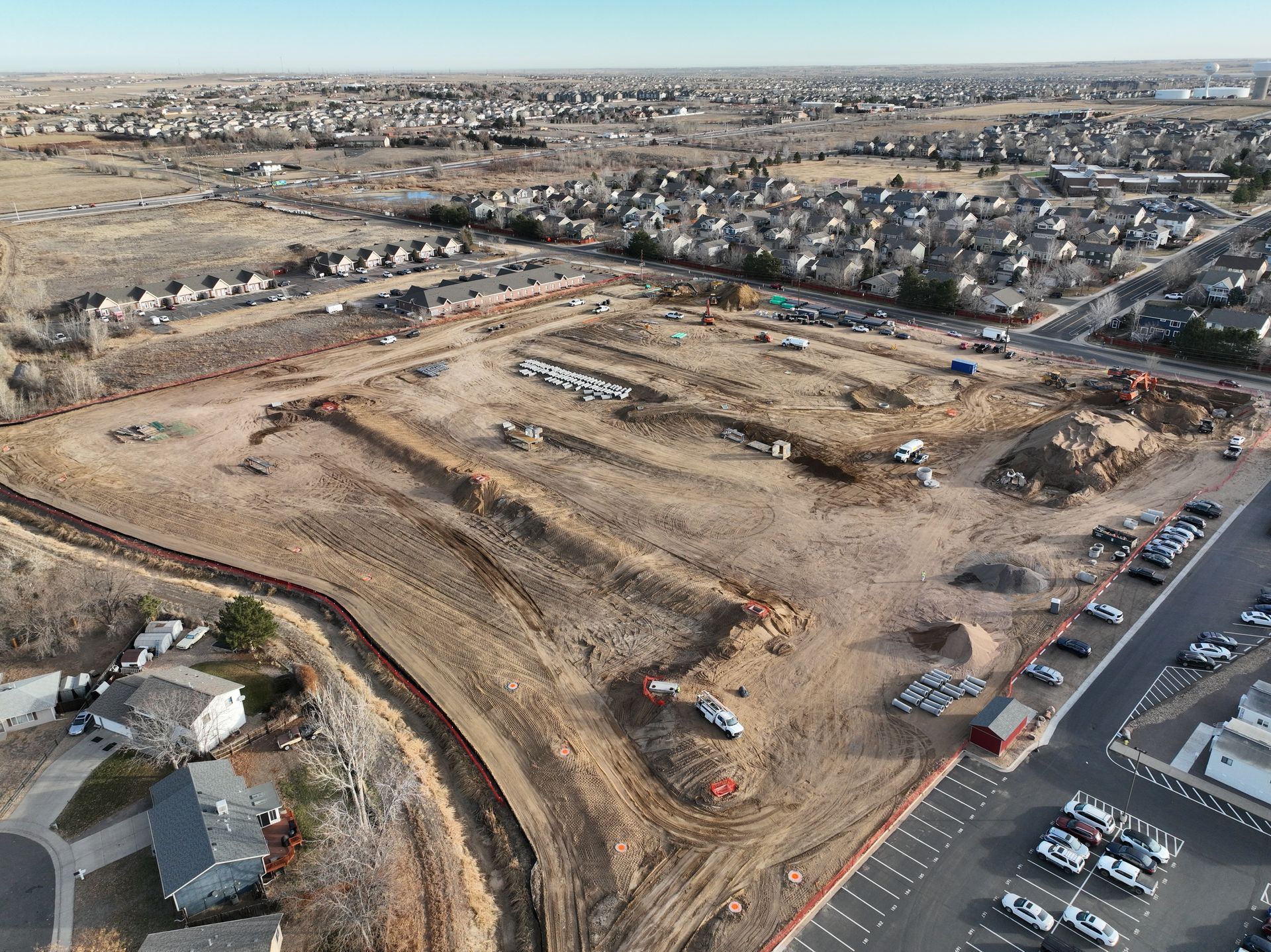 An aerial view of a construction site with a parking lot in the foreground.
