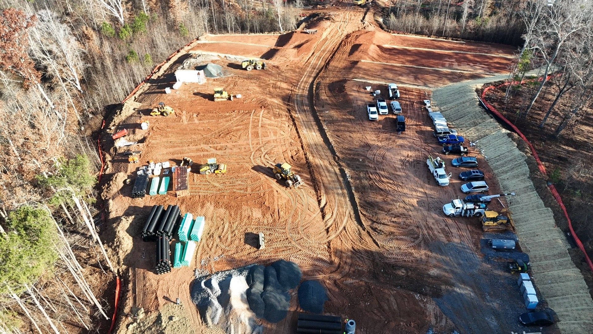 An aerial view of a construction site with a lot of cars parked on the side of the road.