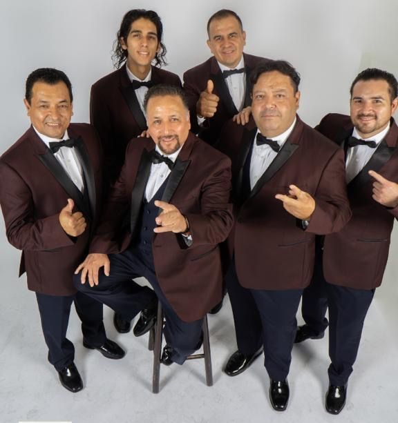 A group of men in tuxedos and bow ties are posing for a picture