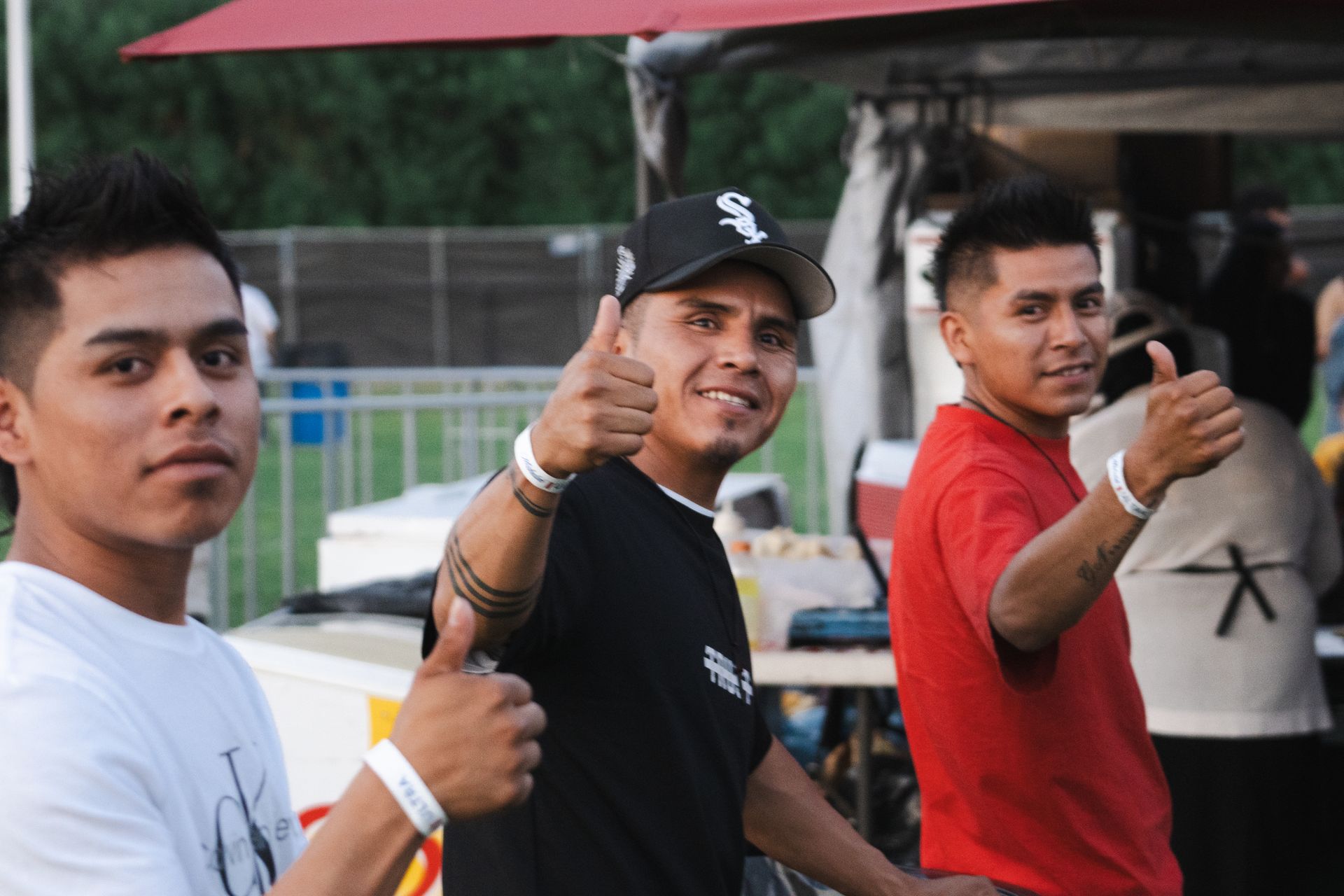 Three young men are standing next to each other and one of them is giving a thumbs up.