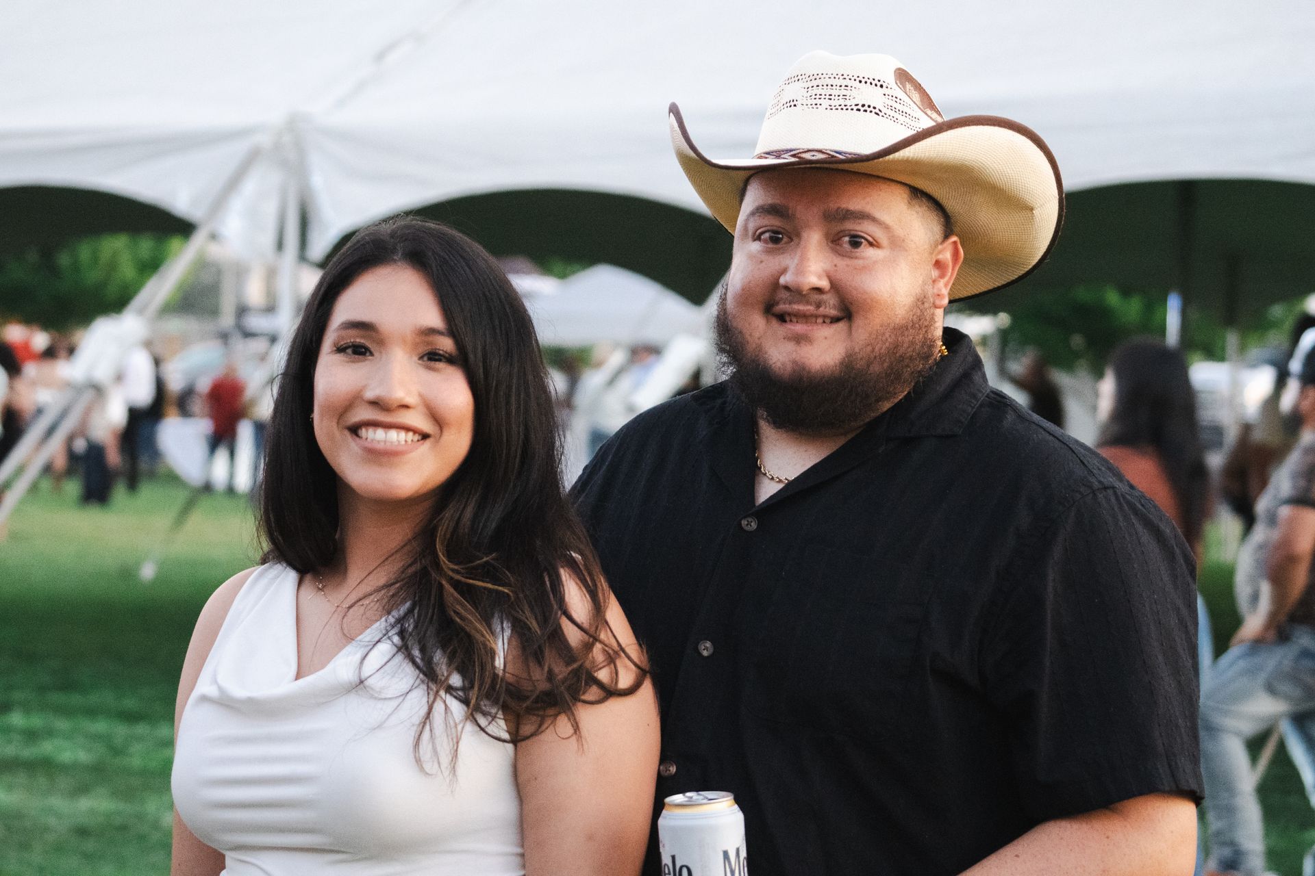 A man in a cowboy hat is standing next to a woman in a white dress.
