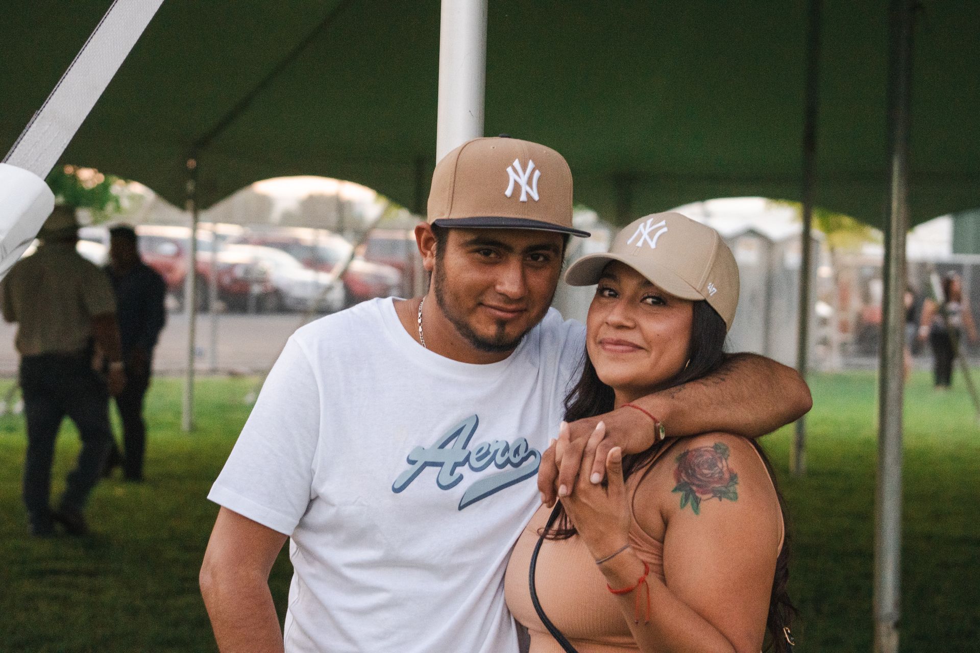 A man and a woman are posing for a picture under a tent.