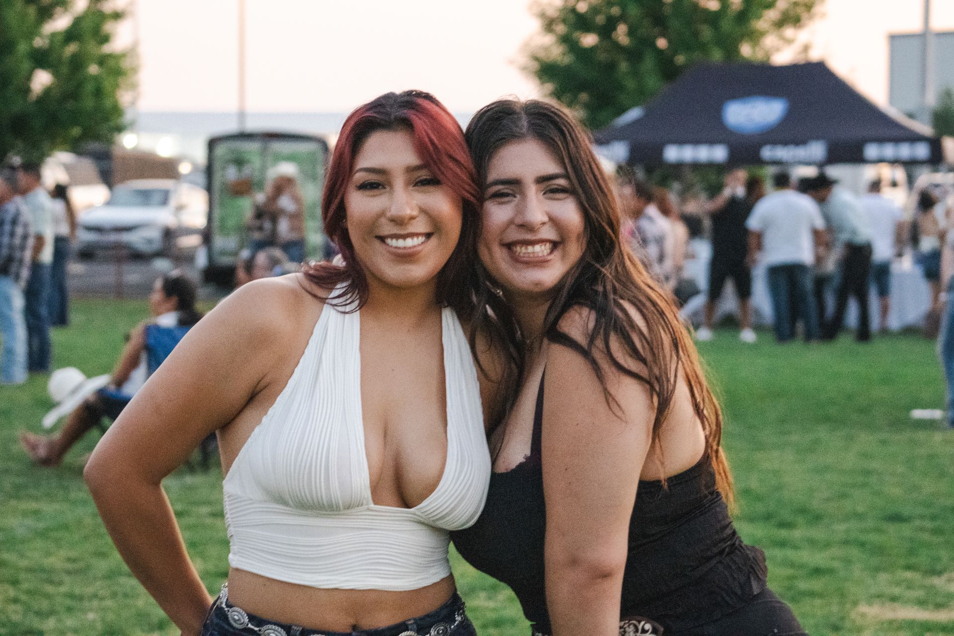 Two women are posing for a picture together in a park.