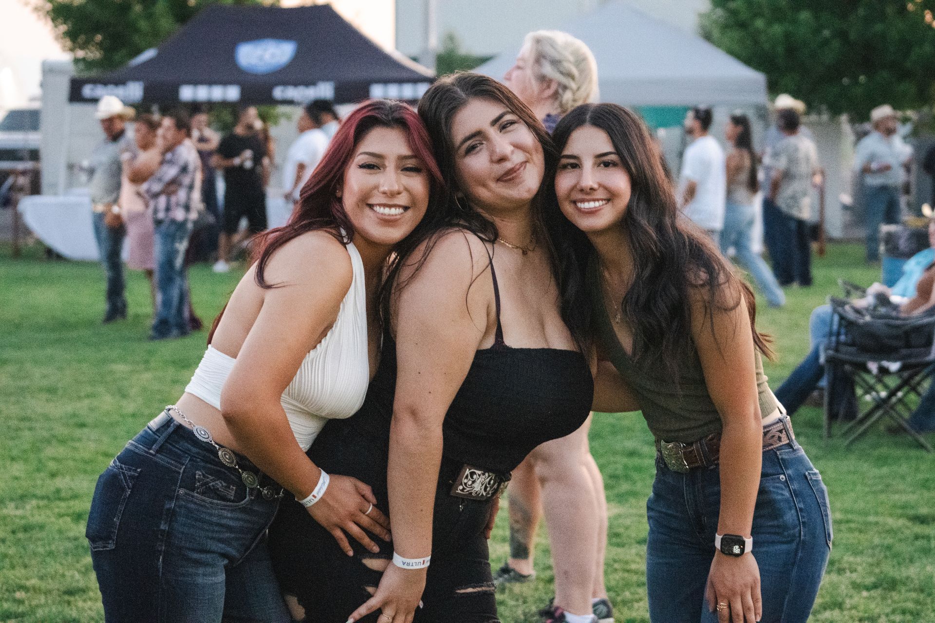 Three women are posing for a picture together in a field.