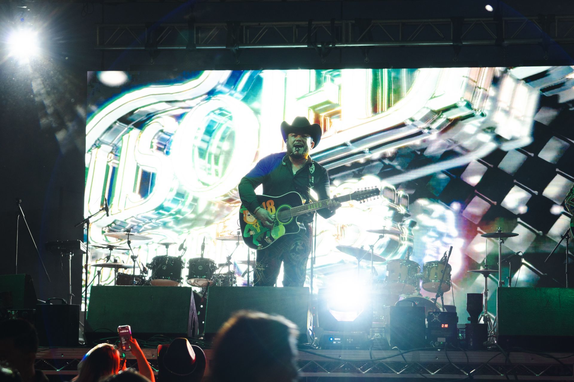 A man in a cowboy hat is playing a guitar on stage