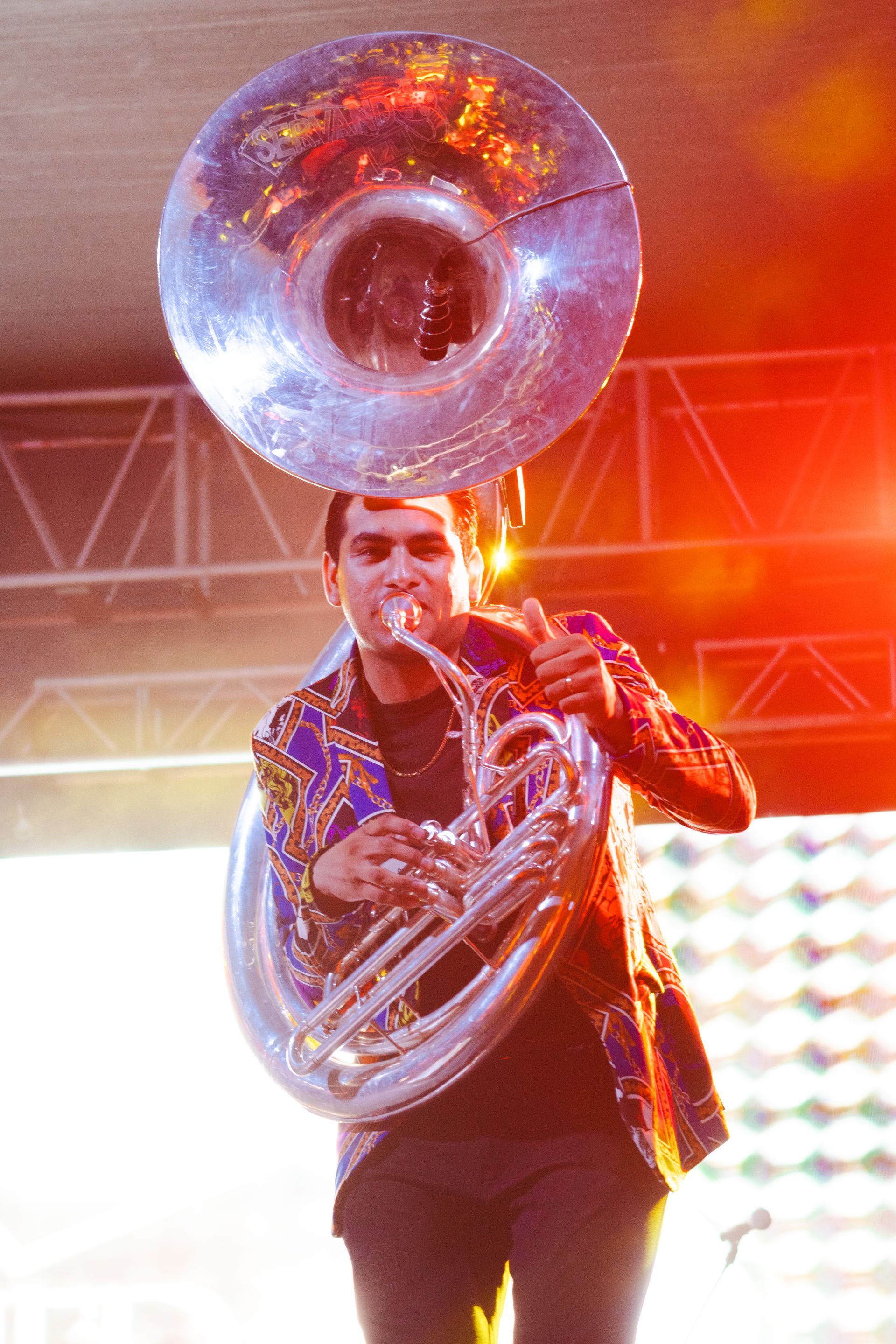 A man in a colorful jacket is playing a brass instrument
