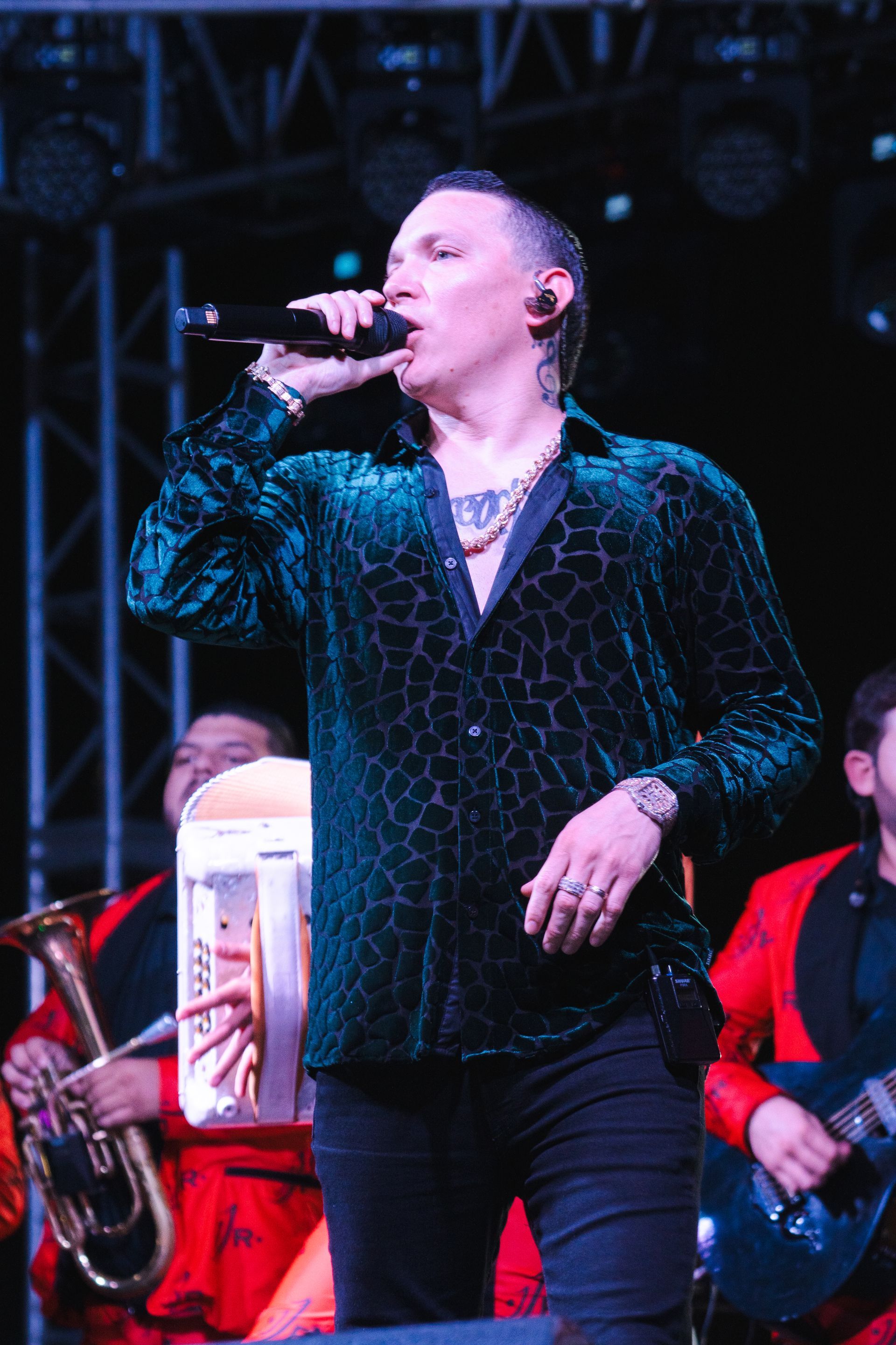 A man in a green shirt is singing into a microphone on a stage.