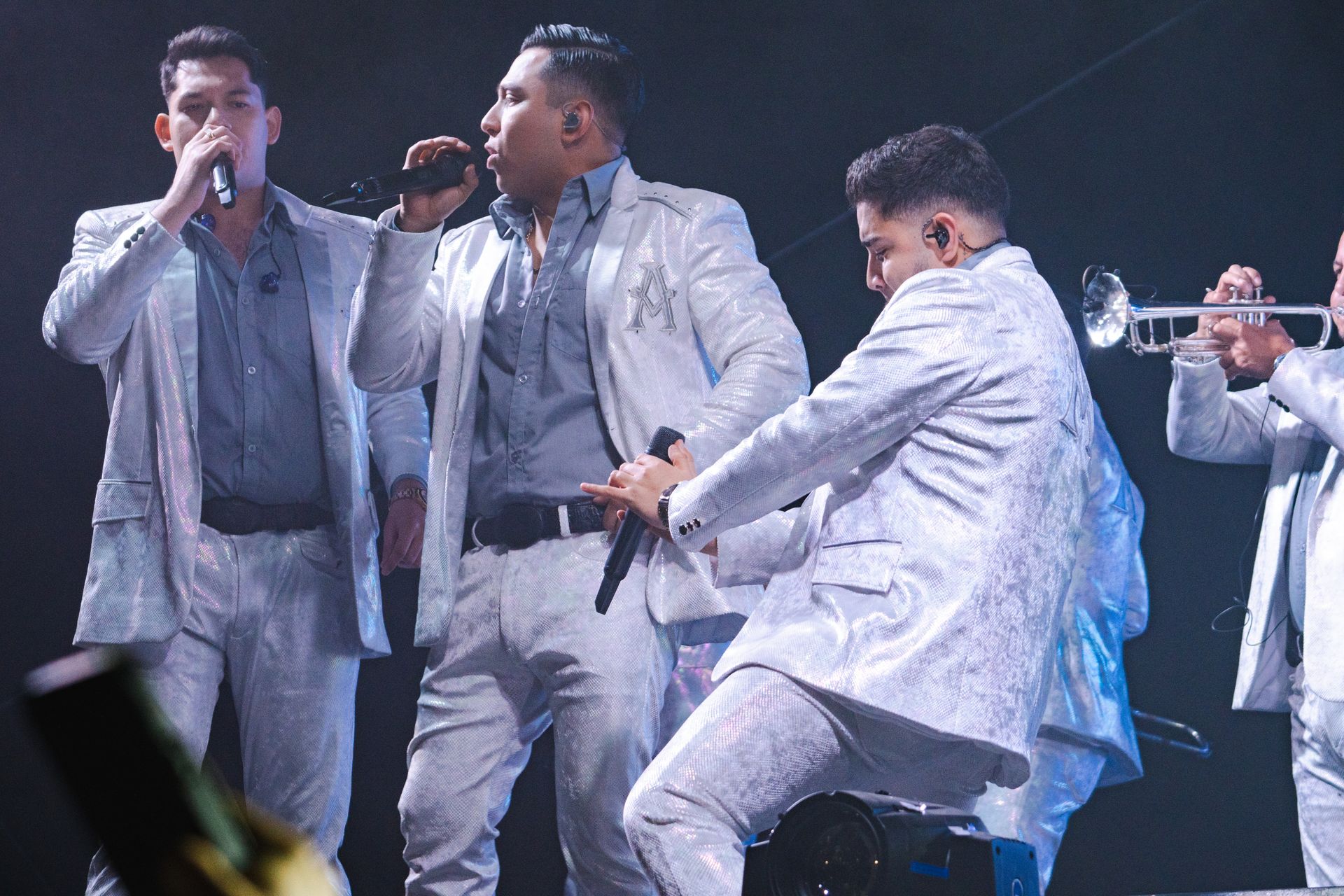 A group of men in suits are singing and playing instruments on a stage.