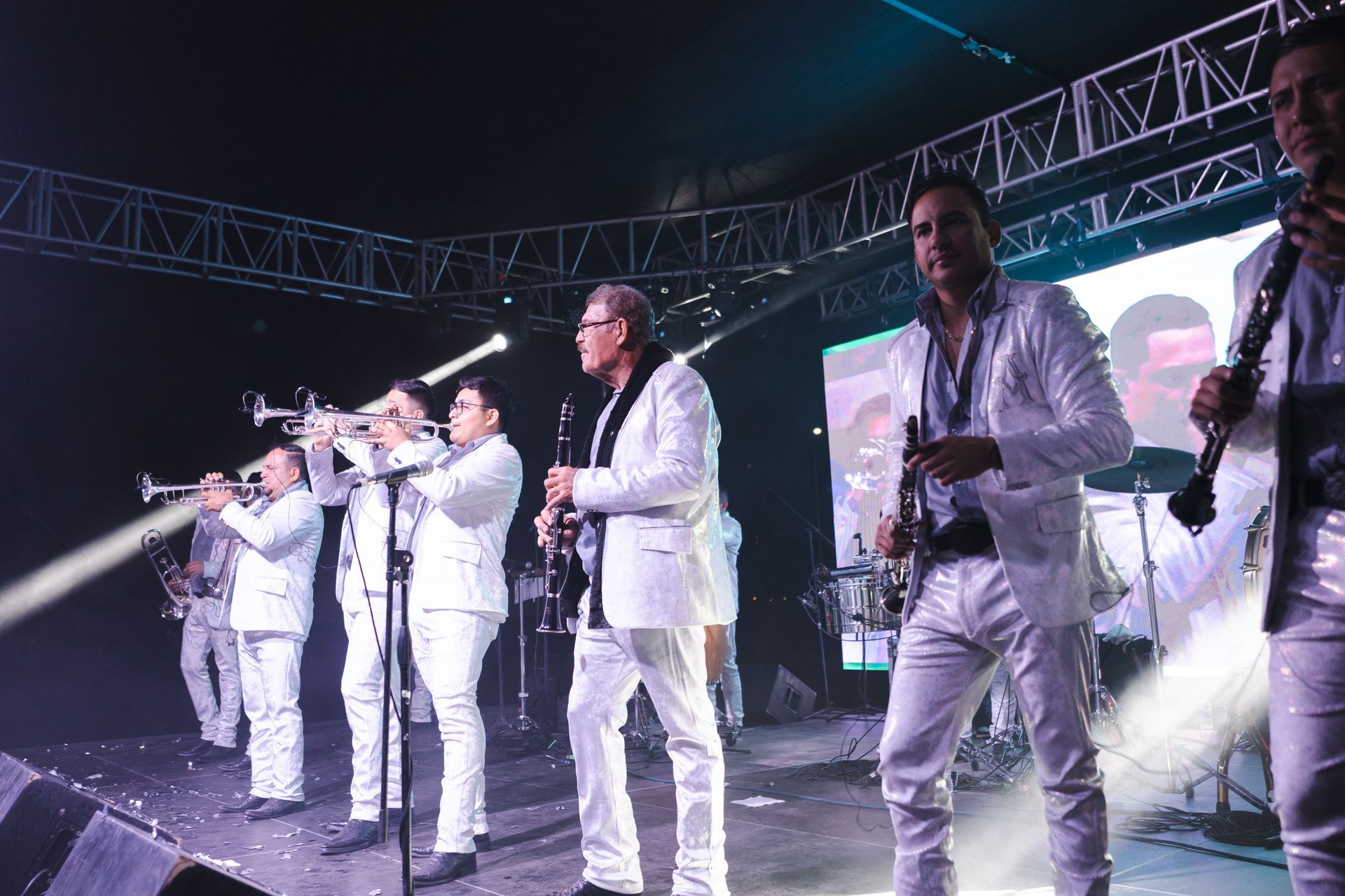 A group of men in white suits are playing instruments on a stage.