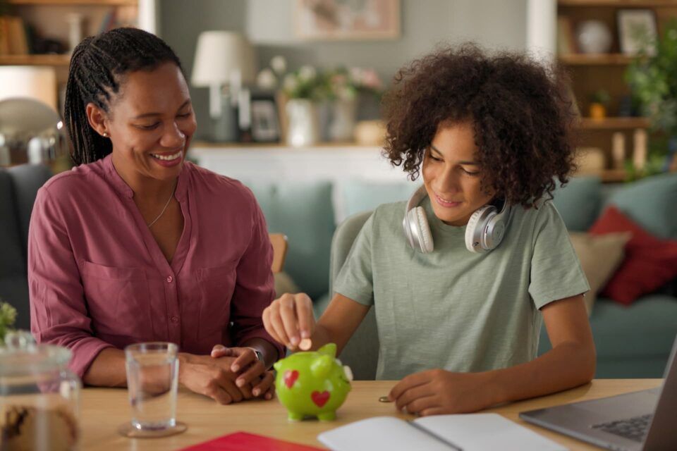 Two people smiling and working together at a table with a laptop and green apple in a cozy room
