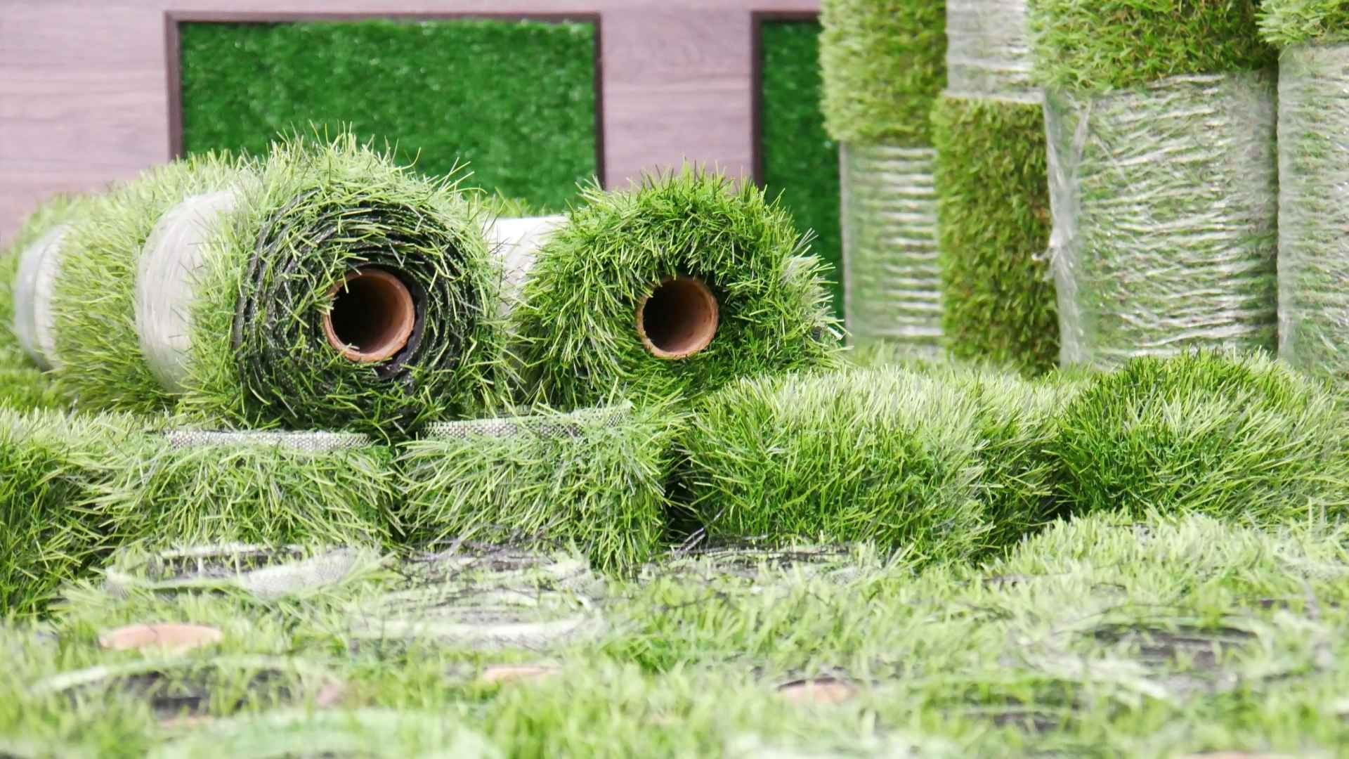 Rolls of artificial grass are sitting on top of each other in a field.