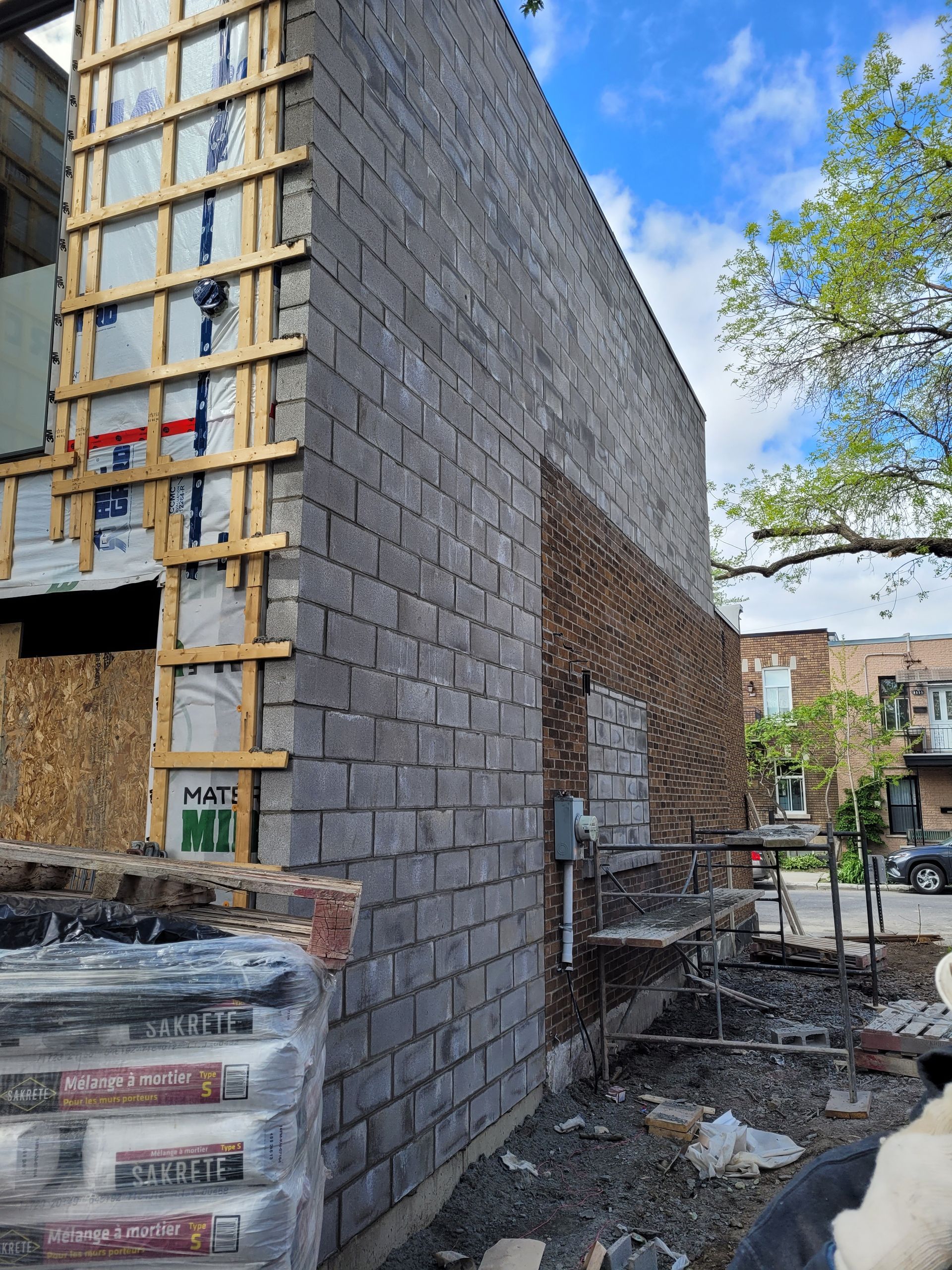 Un bâtiment est en cours de construction avec des briques et des échafaudages.