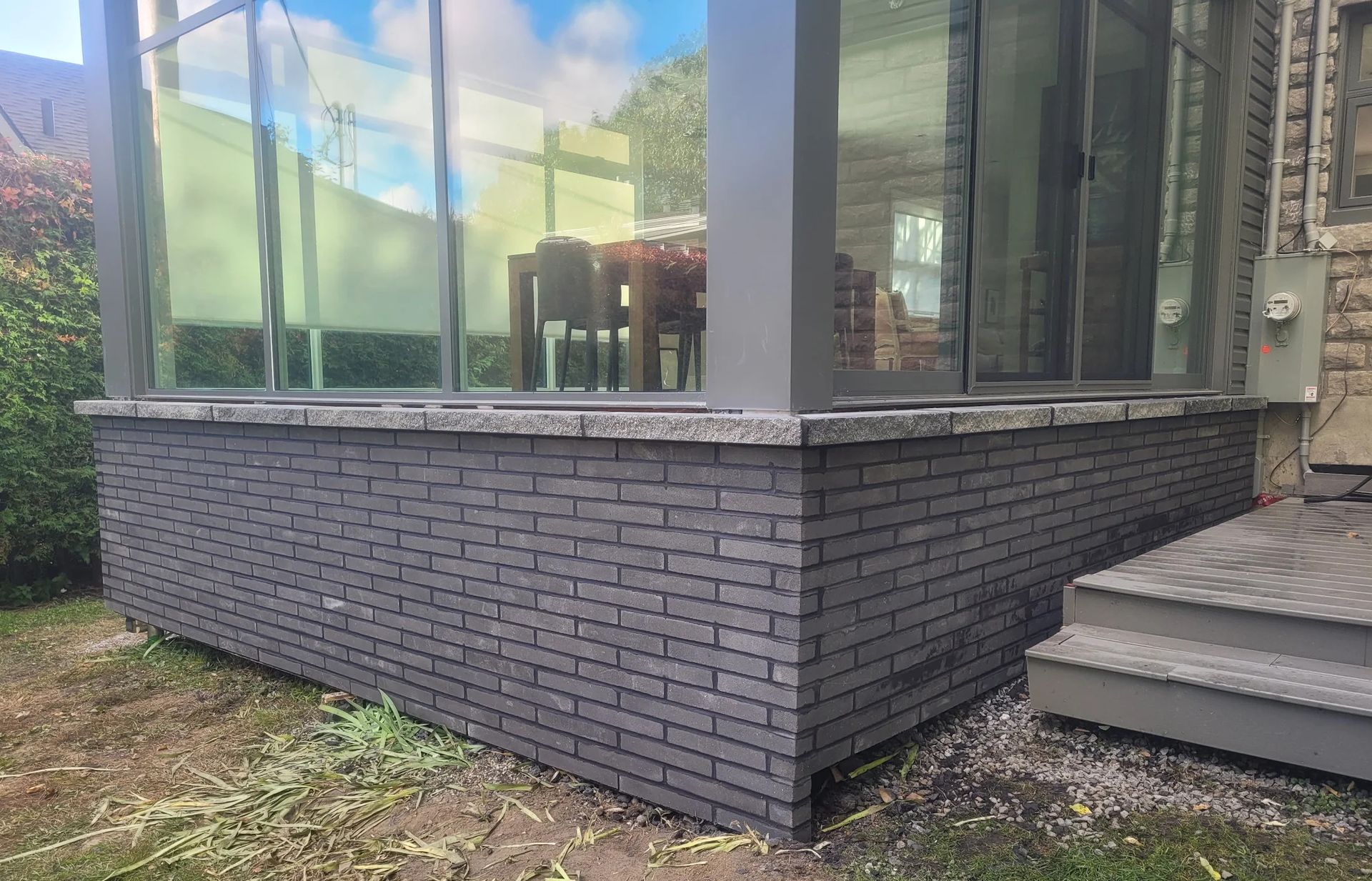 Une véranda avec un mur de briques et des portes coulissantes en verre.