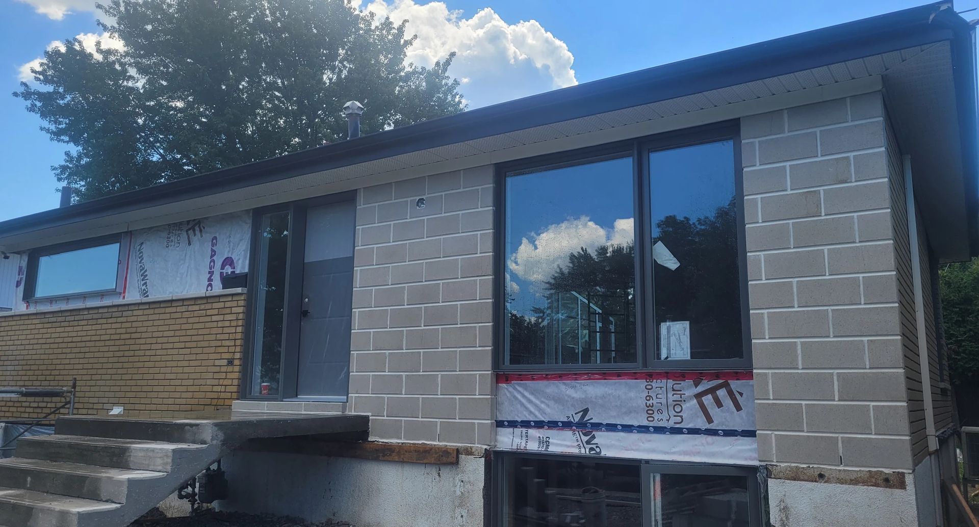 Une maison en briques avec un toit noir et des escaliers devant.
