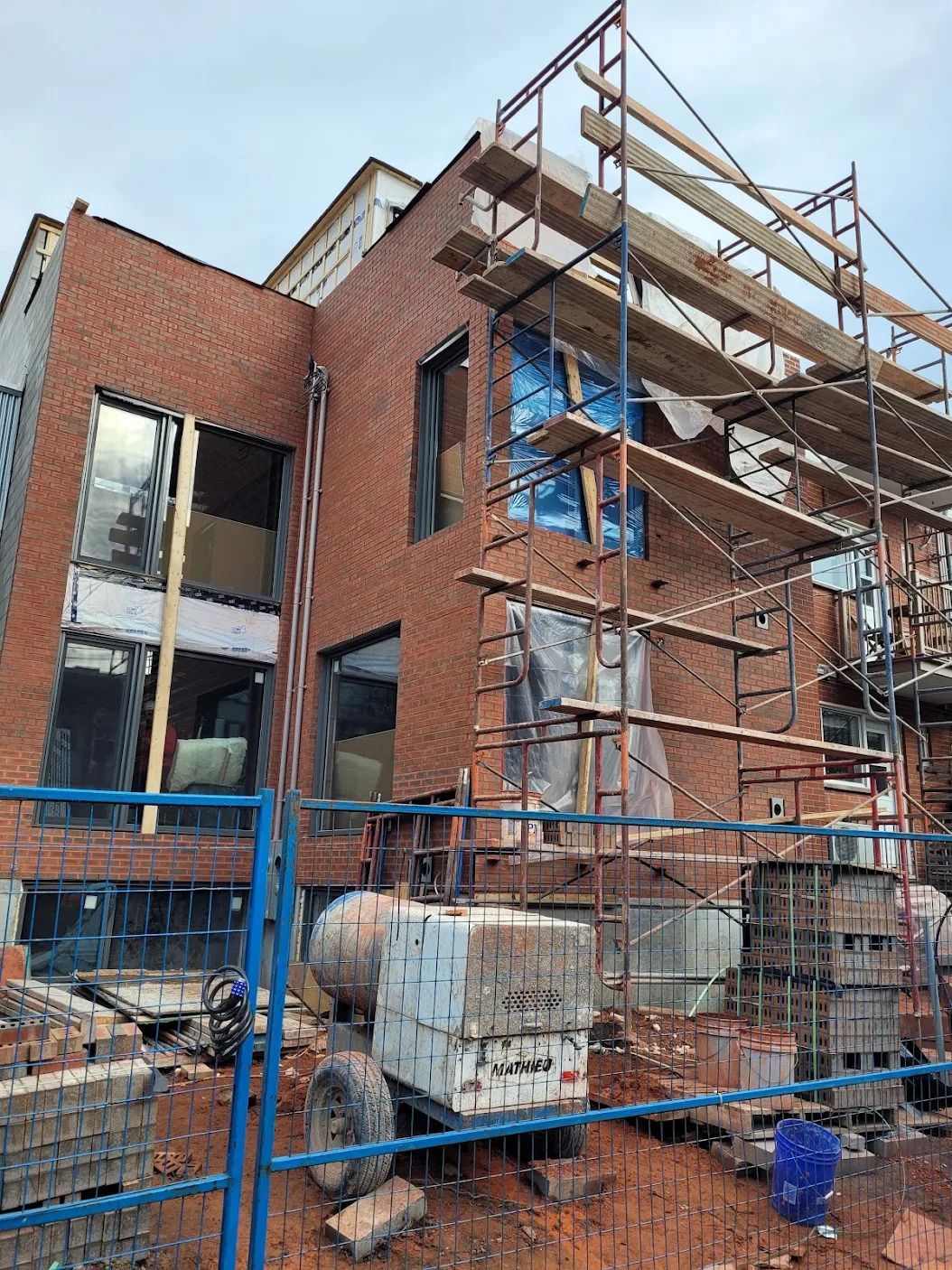 Un grand bâtiment en briques est en cours de construction avec des échafaudages autour.