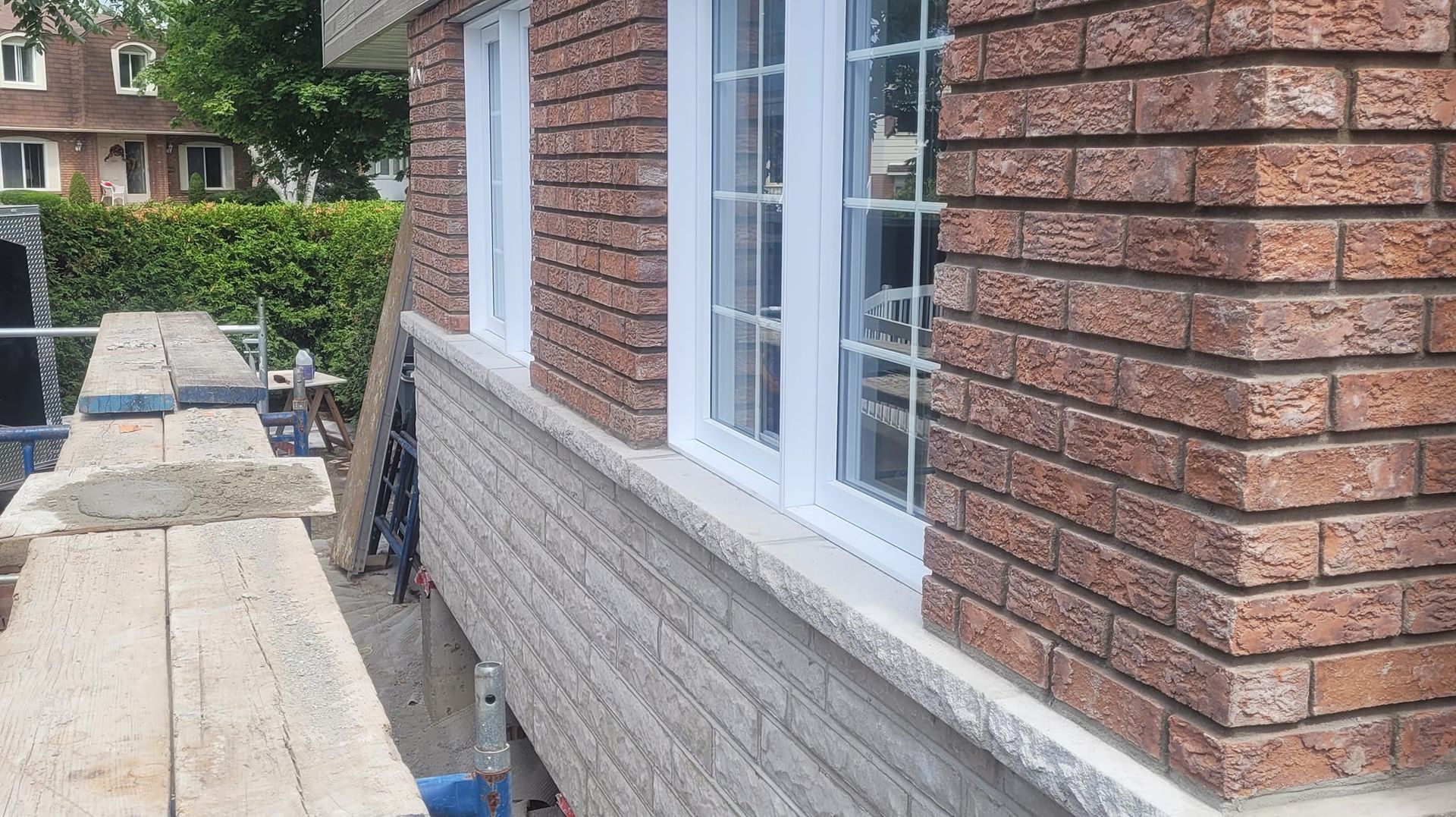 Un bâtiment en briques avec des fenêtres blanches et un échafaudage en bois devant.