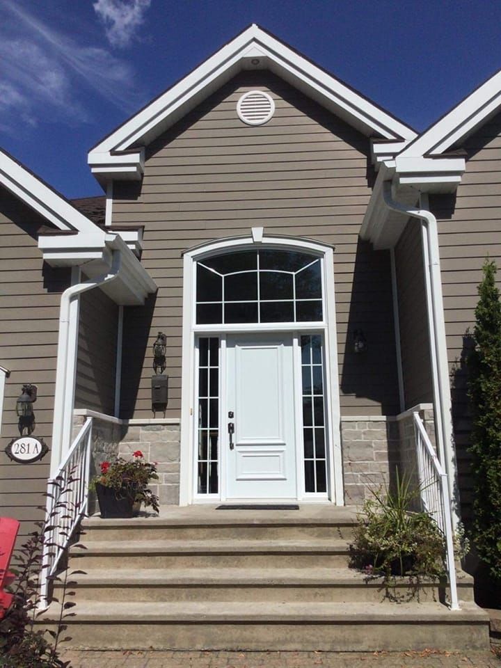 La façade d'une maison avec une porte blanche et des escaliers