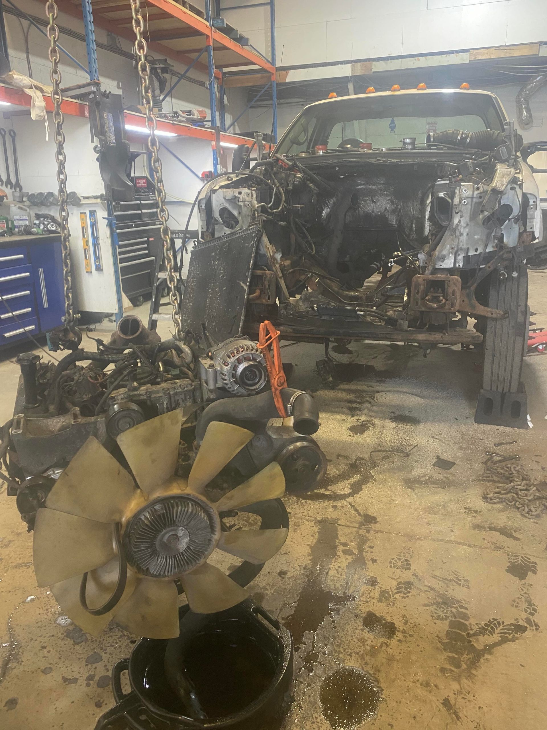 The engine of a truck is being dismantled in a garage.