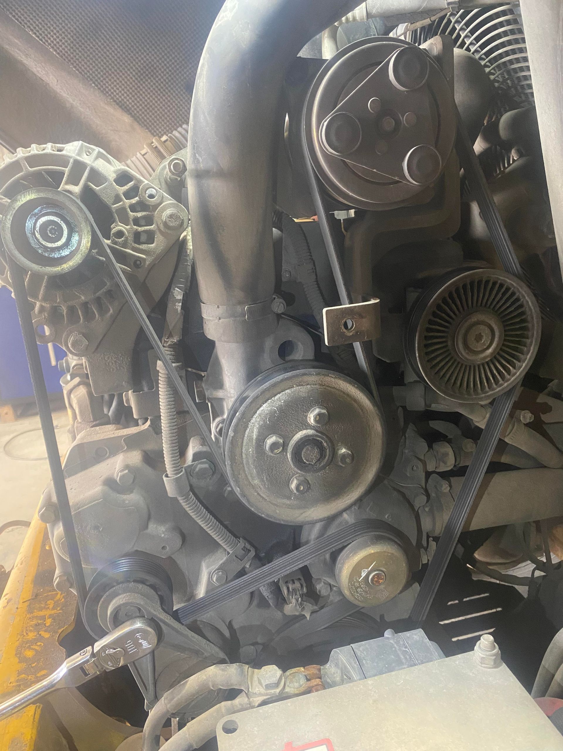 A close up of a car engine with belts and alternators.