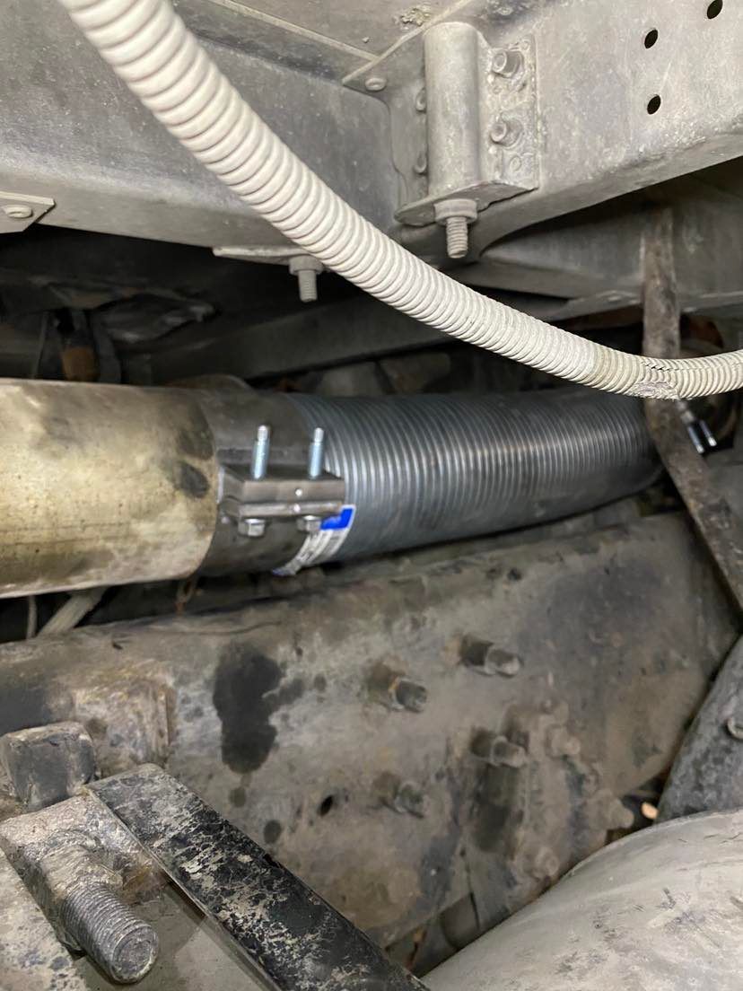 A close up of a hose attached to the underside of a vehicle.