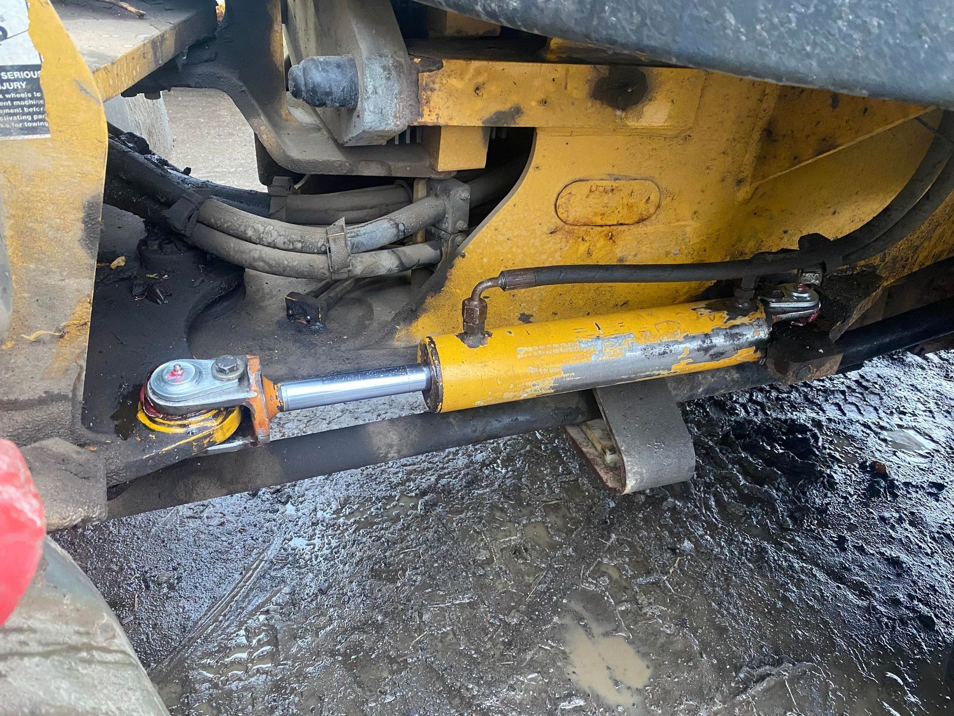 A close up of a hydraulic cylinder on a yellow vehicle.