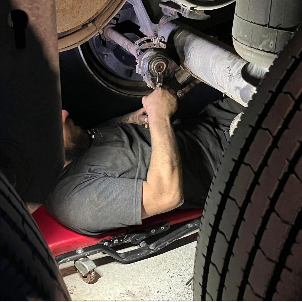 Un homme travaille sous une voiture avec une clé