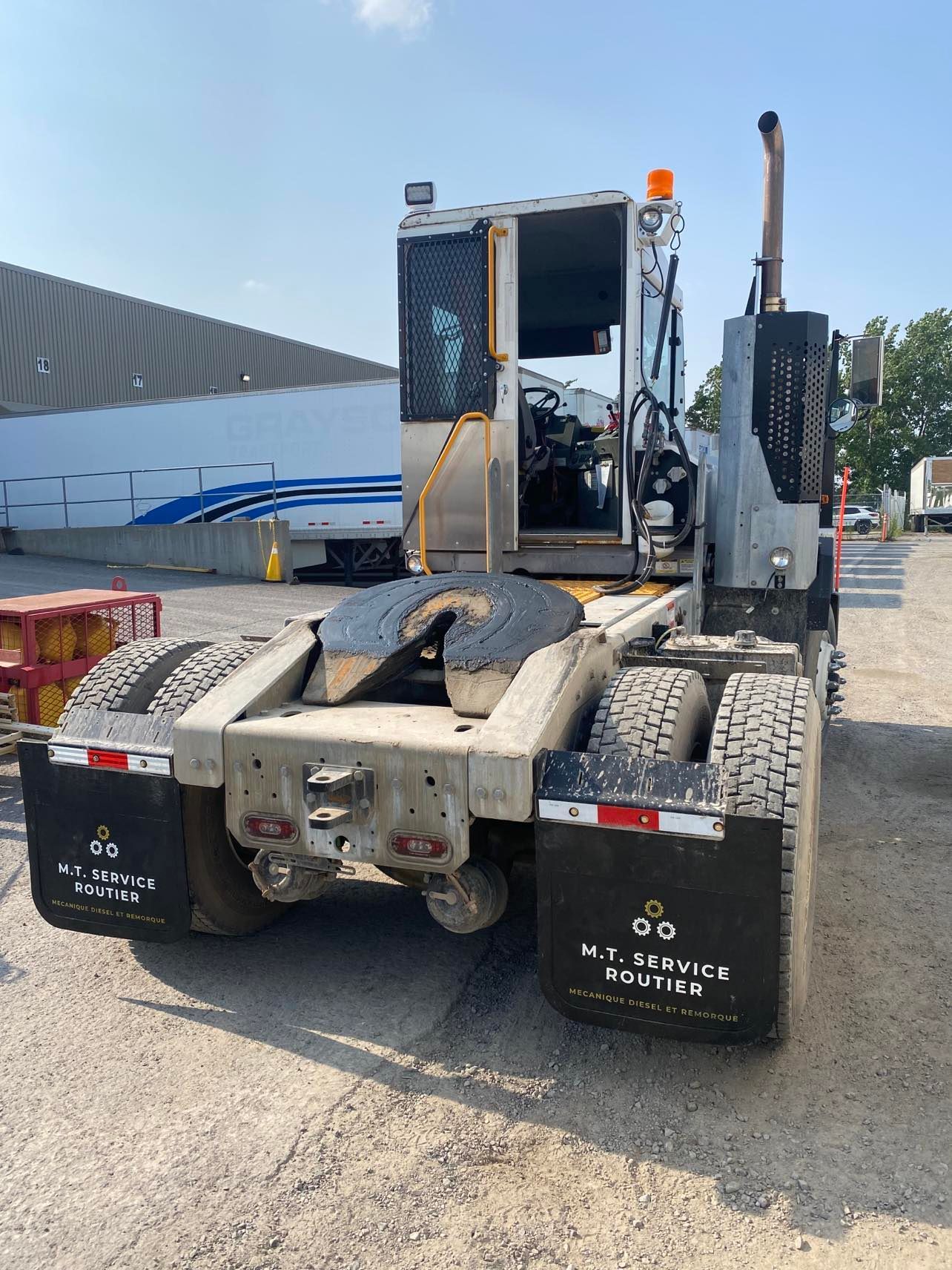 Un semi-remorque avec une remorque attachée est garé sur un parking.
