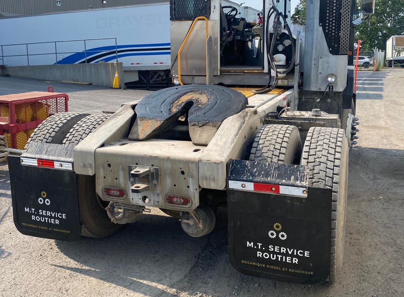 Vue arrière d'un semi-remorque sale, bavettes portant l'inscription « MT SERVICE ROUTER »