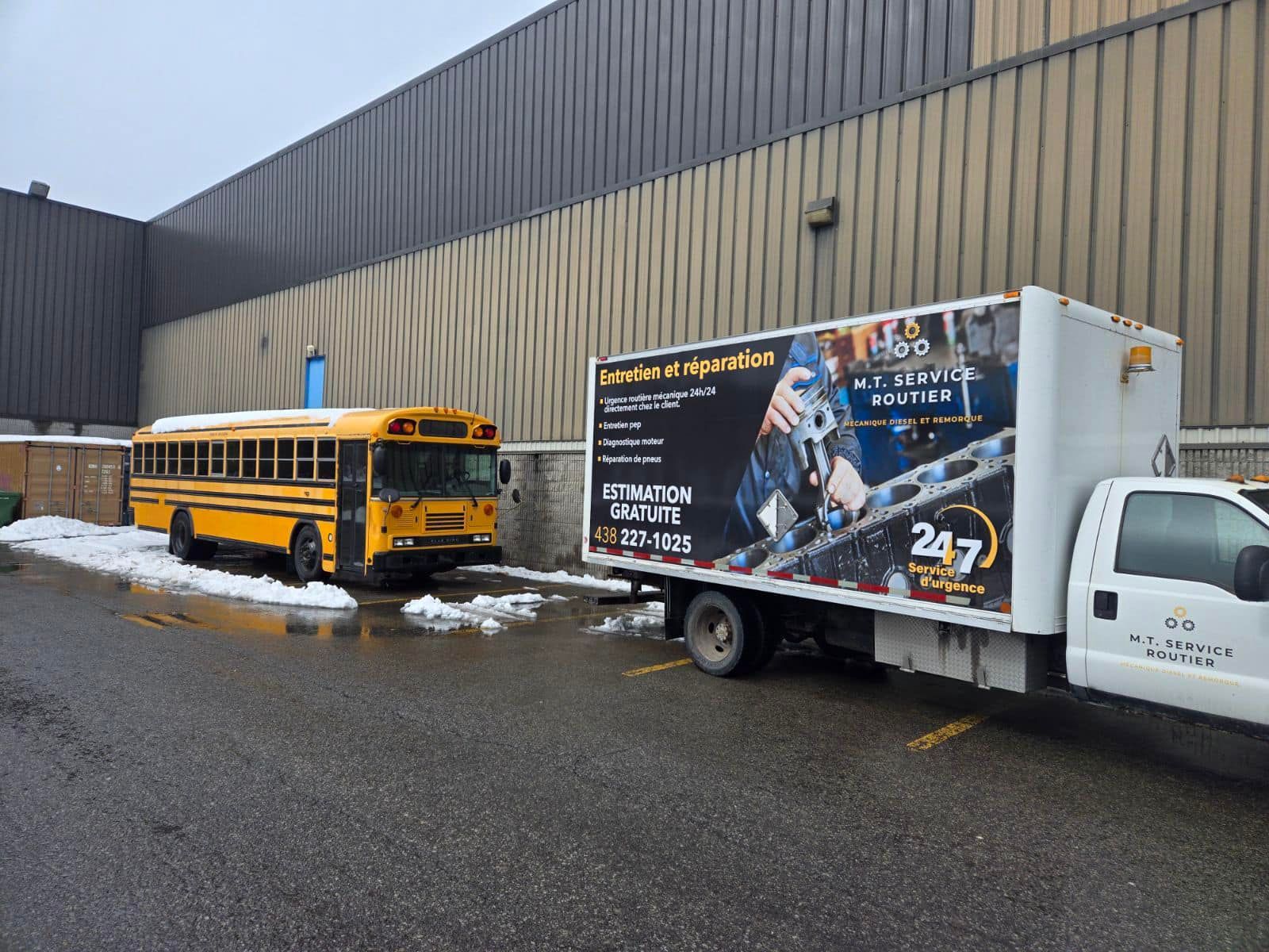Un autobus scolaire jaune et un camion blanc sont stationnés à côté d'un bâtiment dans une zone humide et enneigée.