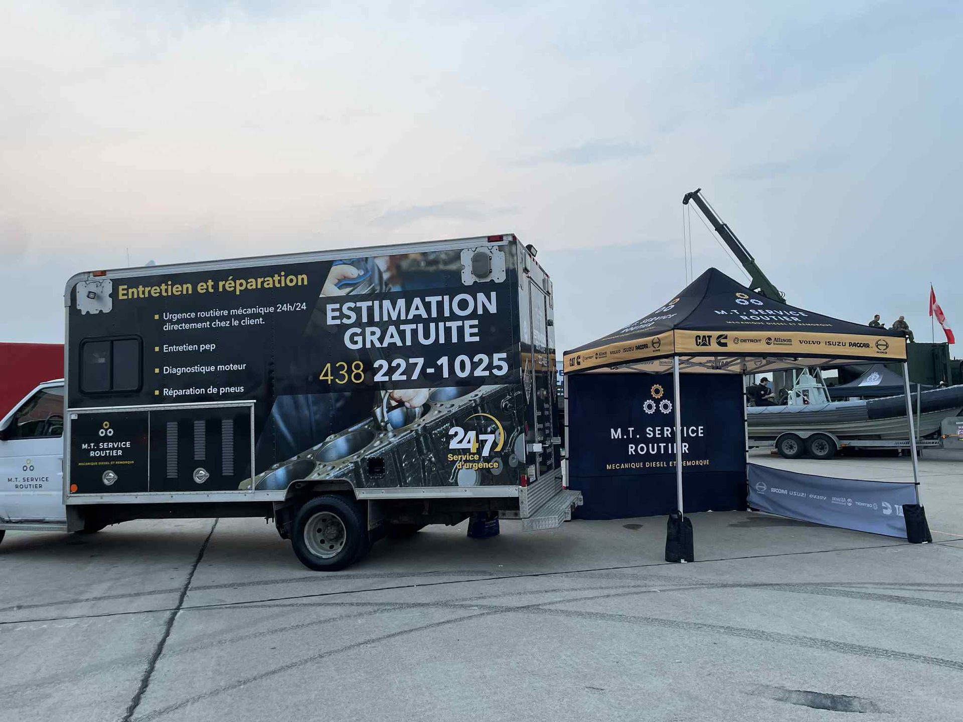 Camion blanc avec panneaux noirs proposant des devis gratuits, tente installée à proximité.