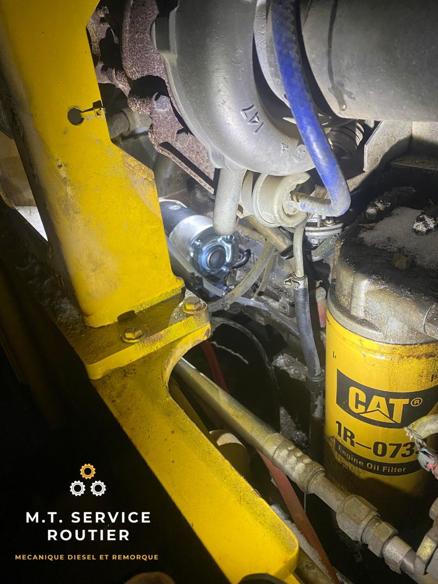 A cat oil filter is sitting on top of a yellow engine.