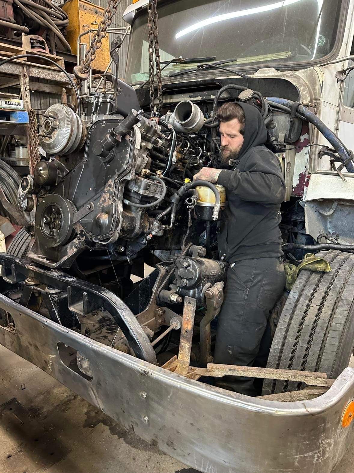 A man is working on the engine of a truck.
