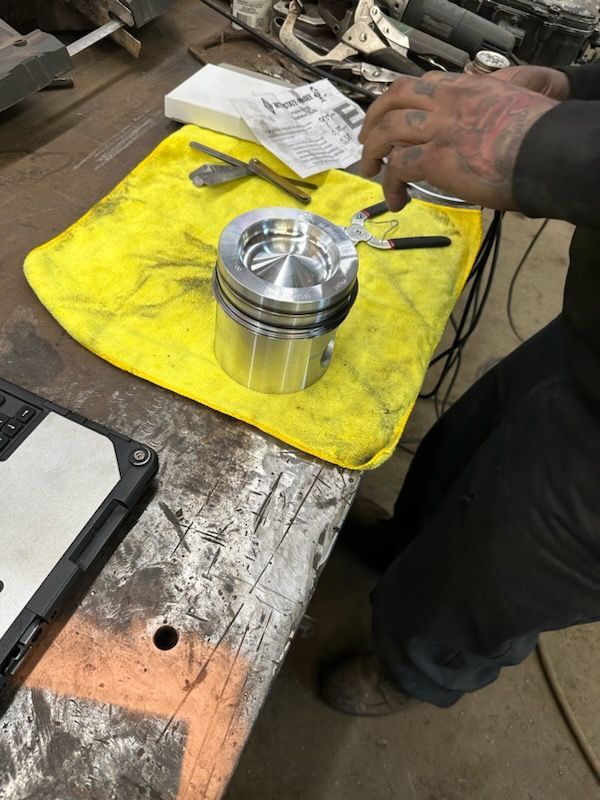 A man is working on a piston on a yellow towel