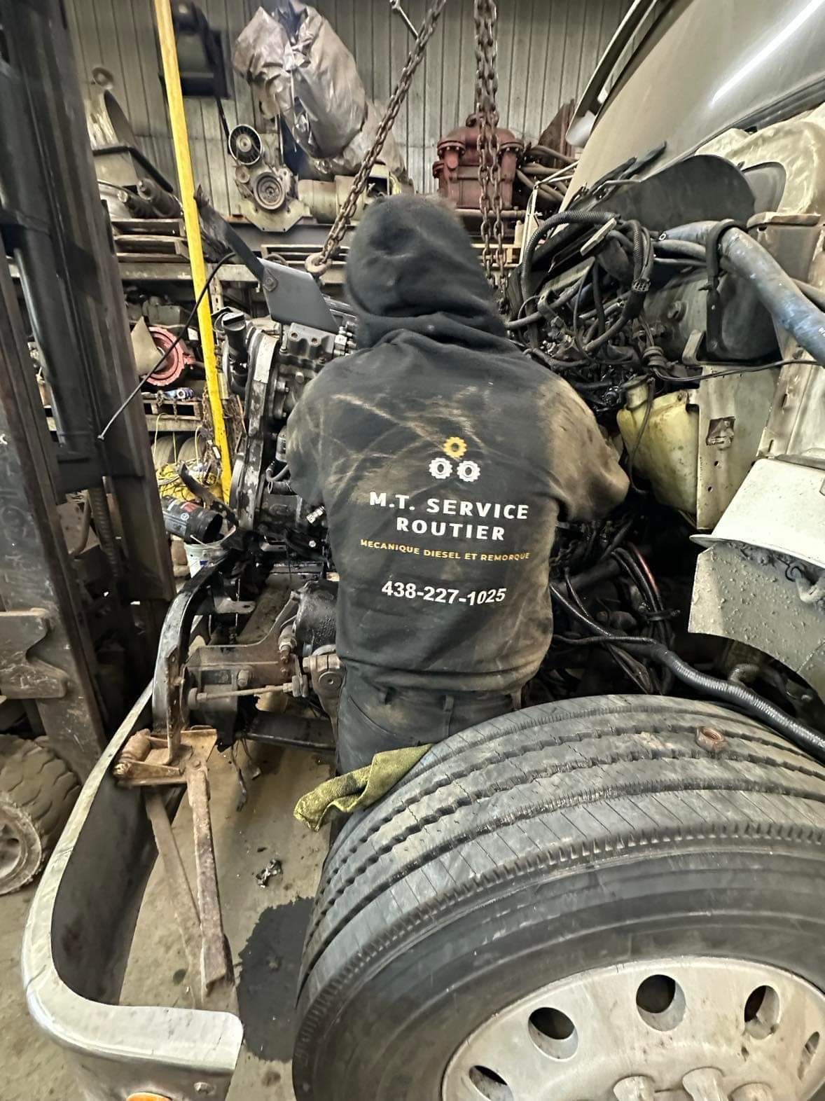 Un homme travaille sur le moteur d'un camion dans un garage.