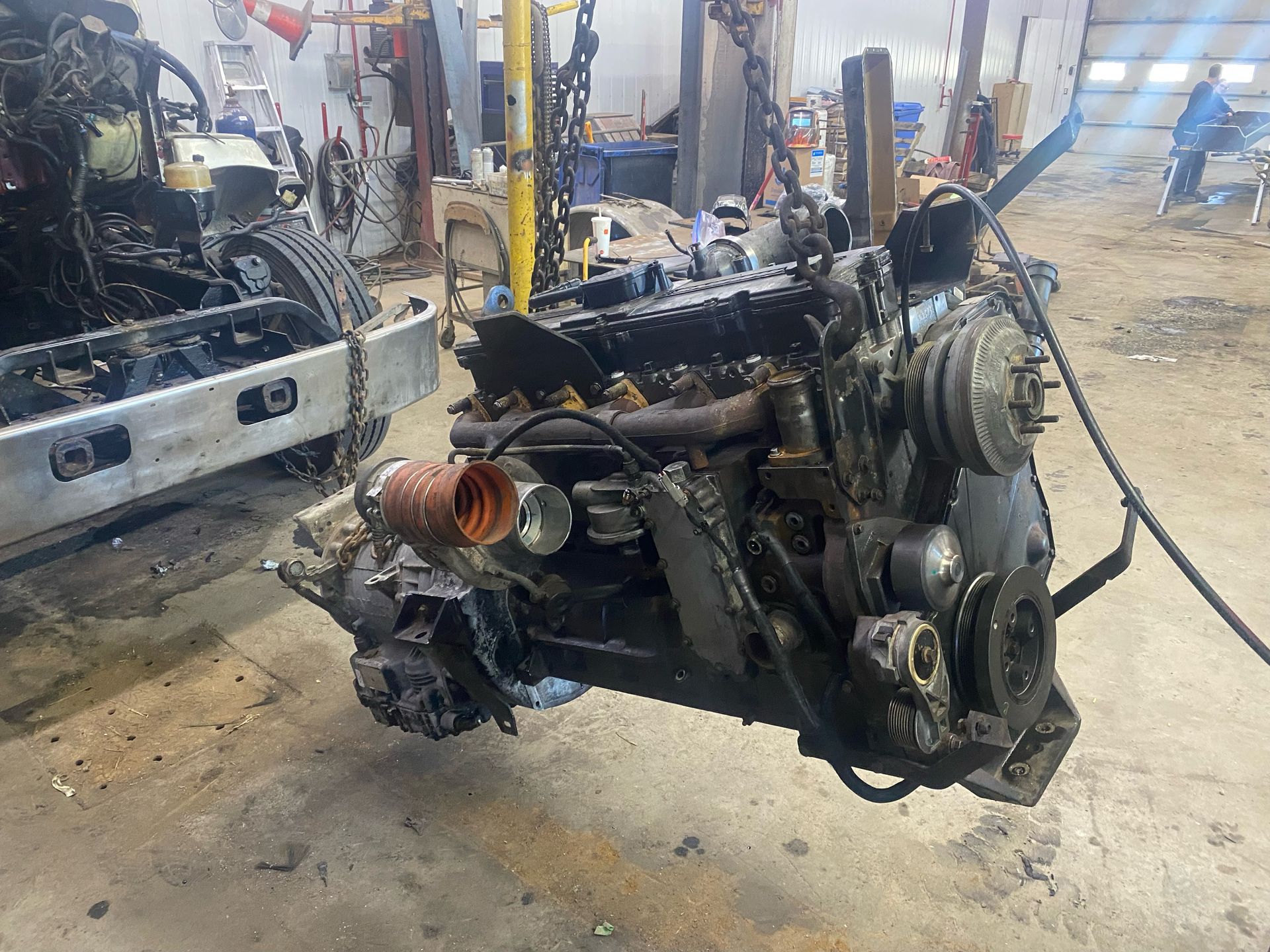 A large engine is being dismantled in a garage.