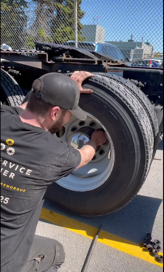 Un mécanicien retire les écrous de roue d'un pneu de semi-remorque à l'extérieur.
