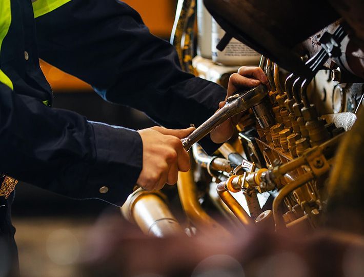 Un mécanicien utilise une clé pour réparer une machine. Gros plan sur des mains travaillant sur un moteur de couleur or.