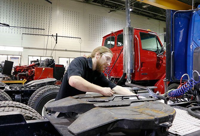 Un homme travaille sur un semi-remorque dans un garage.