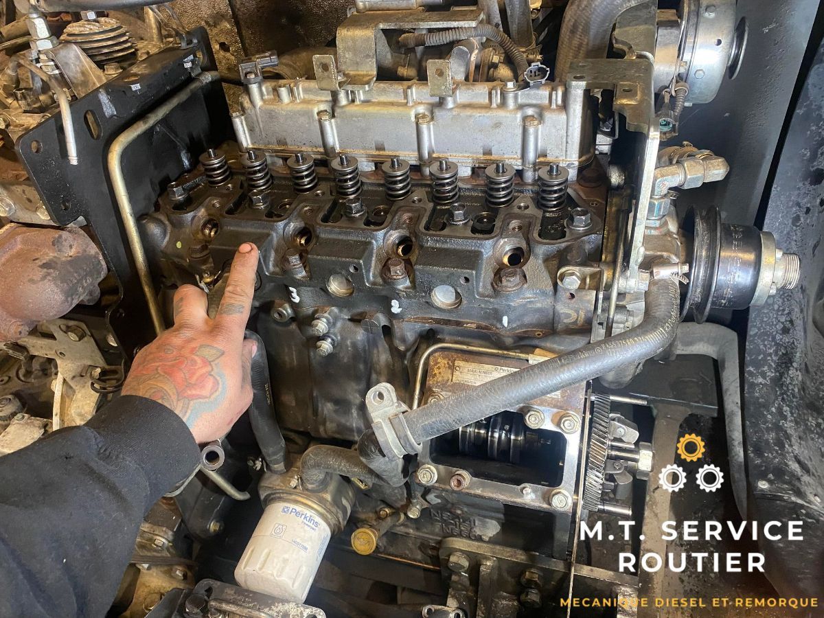 A man is pointing at a dirty engine in a garage.
