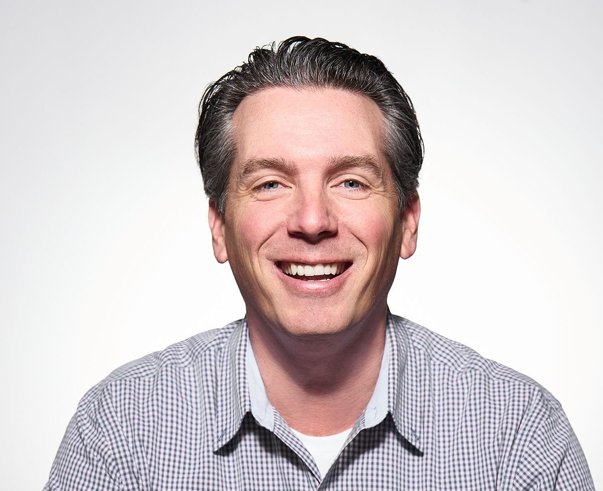 A man in a plaid shirt is smiling for the camera