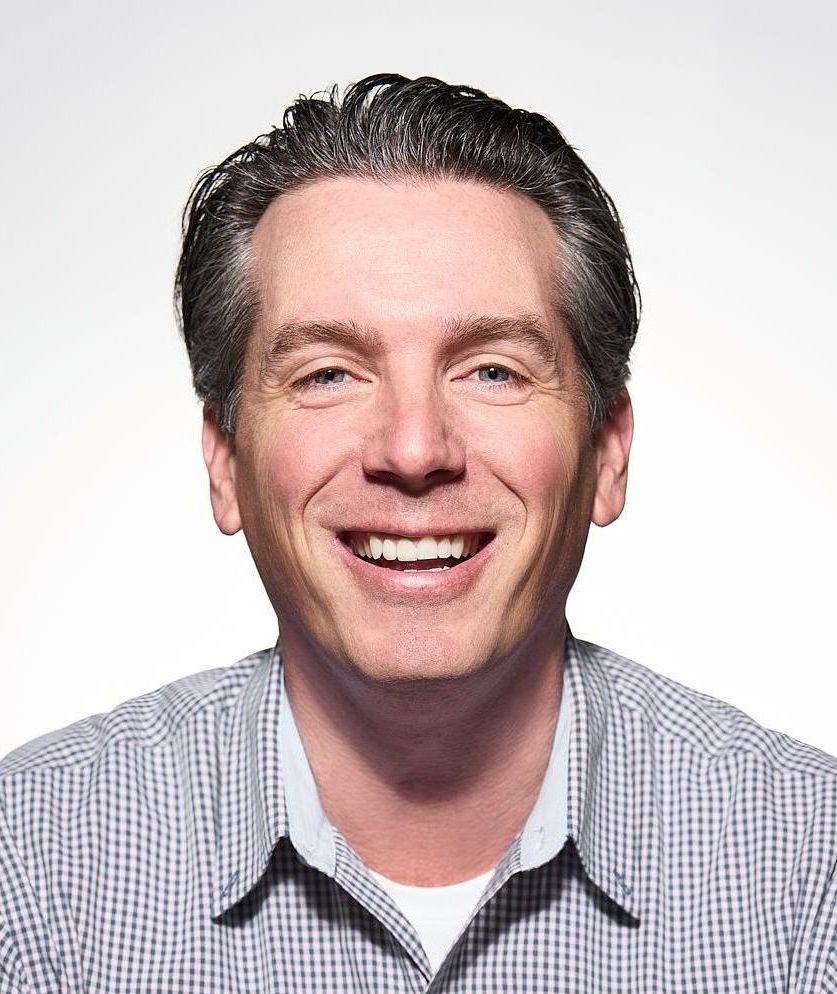 A man in a plaid shirt is smiling for the camera.